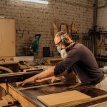 Experienced woodworker using a table saw in a well-equipped woodworking shop.