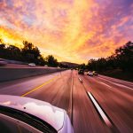 Motion blur of cars speeding on an Irvine highway at sunset with vibrant skies.