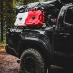 a black truck with a red and white cooler on the back of it
