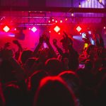 People standing on stage with lights turned on during nighttime party in Ottawa
