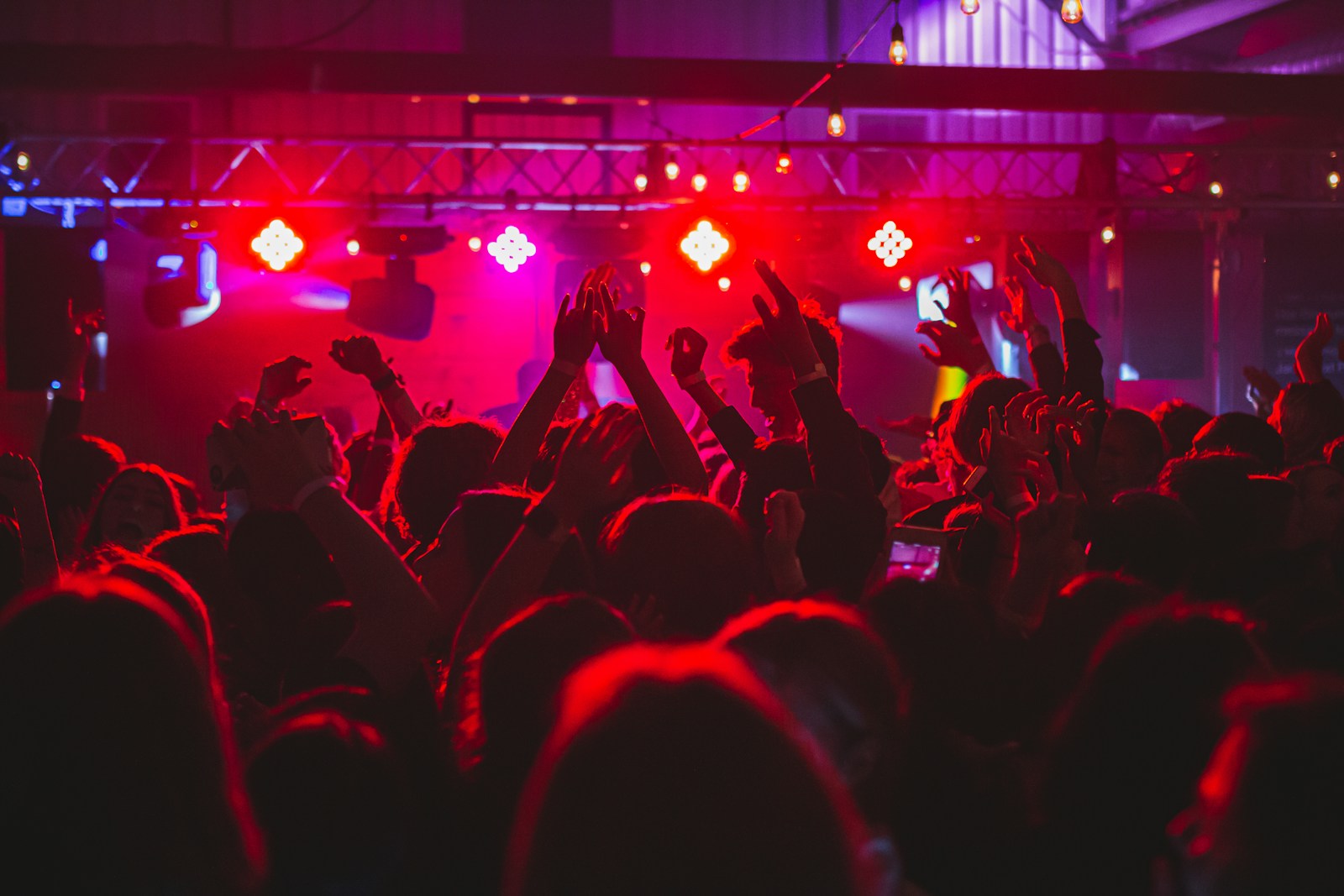 People standing on stage with lights turned on during nighttime party in Ottawa